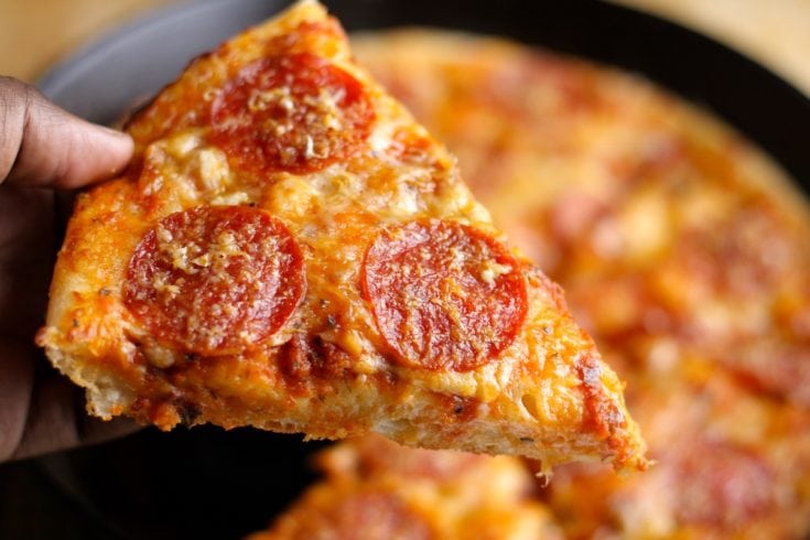 https://www.thehungryhutch.com/wp-content/uploads/2017/06/Cast-Iron-Pizza-Pepperoni-Slice-Hand-1-735x490.jpg